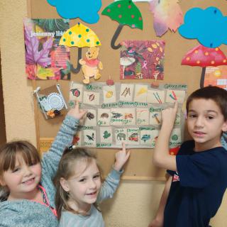 Dzieci klasy 0 prezentujące prace plastyczne tworzone na zajęciach logopedycznych.