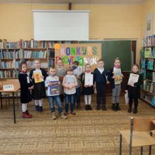 Uczniowie klas I z nagrodami w bibliotece szkolnej.