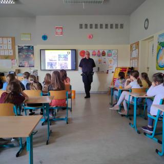 Strażniczka miejska prowadząca zajęcia z uczniami  klasie.