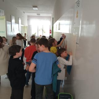 Uczniowie odrysowujący swoją dłoń na plakacie.