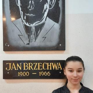 Zuzanna Kowalska stoi na tle wizerunku Jana Brzechwy