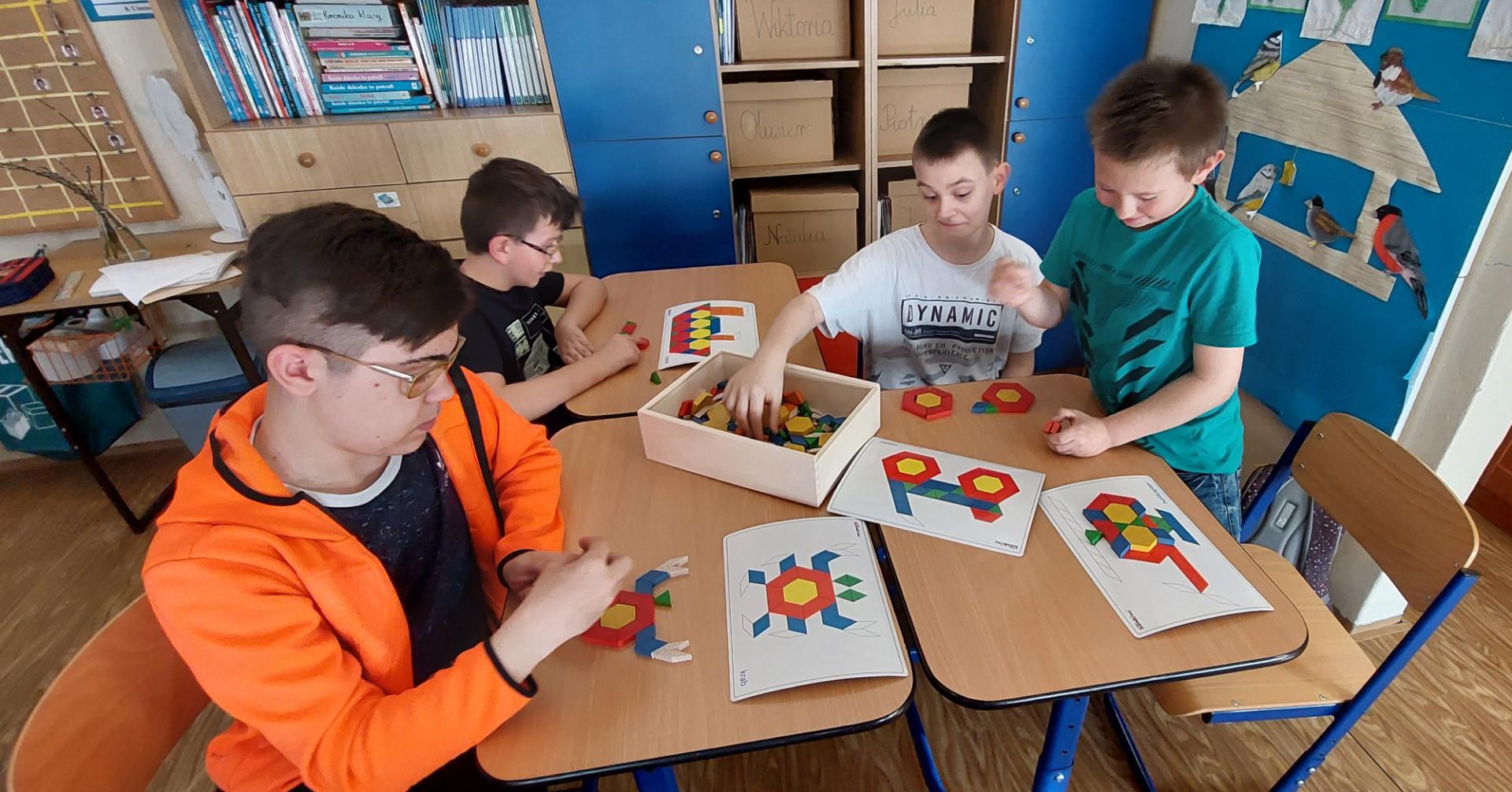 Czterech chłopców przy stolikach układa mozaikę geometryczną