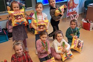 7 dziewczynek z bukiecikami tulipanów oraz paczuszkami słodyczy