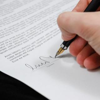 Dłoń z piórem podpisująca dokument