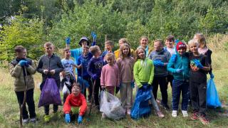 Grupa dzieci z workami na śmieci na tle natury