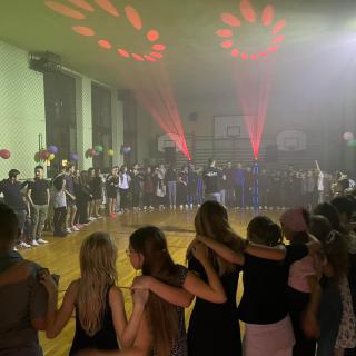 Uczniowie tańczący w sali gimnastycznej podczas zabawy andrzejkowej.